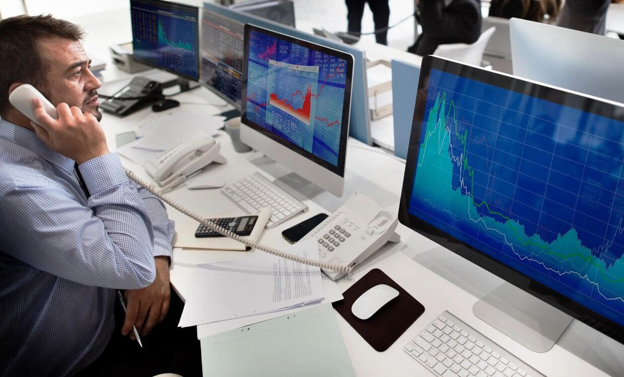 A man sitting at a desk with several computers.